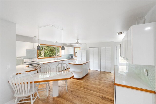 1117 Gopher Ridge Rd, Fort Pierce, FL 34982 - kitchen with white appliances, light countertops, backsplash, light wood-style floors, and white cabinetry