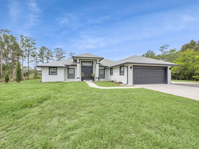 16430 71st Ln N, Loxahatchee, FL 33470 - prairie-style home featuring a garage, driveway, a front yard, stucco siding, and roof with shingles