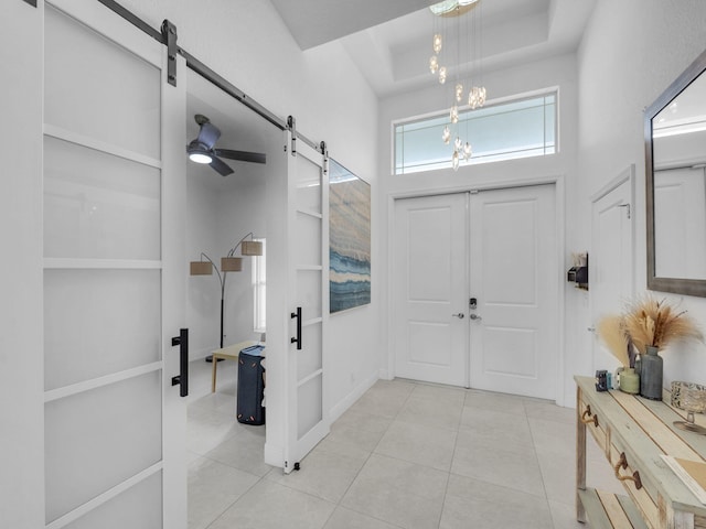 16430 71st Ln N, Loxahatchee, FL 33470 - foyer featuring a barn door, light tile patterned flooring, a chandelier, and a tray ceiling