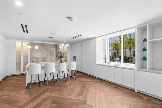 220 SE Mizner Blvd Unit 611, Boca Raton, FL 33432 - kitchen with white cabinetry, light countertops, a sink, open shelves, and a kitchen bar