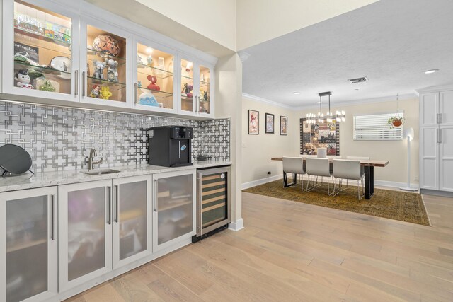 2407 SW 23rd Cranbrook Dr, Boynton Beach, FL 33436 - indoor wet bar featuring crown molding, beverage cooler, backsplash, light wood finished floors, and decorative light fixtures