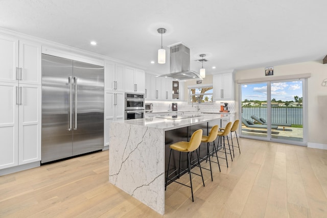 2407 SW 23rd Cranbrook Dr, Boynton Beach, FL 33436 - kitchen with appliances with stainless steel finishes, island range hood, white cabinetry, light wood-style floors, and recessed lighting