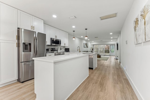 13725 Flora Pl Unit D, Delray Beach, FL 33484 - kitchen with stainless steel appliances, a center island, a peninsula, light wood-type flooring, and white cabinets