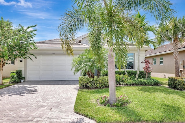 12145 SW Jasper Lake Way, Port Saint Lucie, FL 34987 - view of front of home featuring decorative driveway, stucco siding, a front yard, a tile roof, and a garage