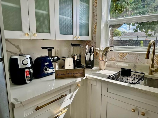 5690 Honeysuckle Dr, West Palm Beach, FL 33415 - kitchen with glass insert cabinets, backsplash, and light stone countertops