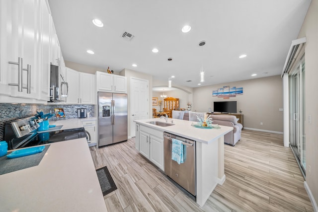 11187 SW Lake Park Dr, Port Saint Lucie, FL 34987 - kitchen with stainless steel appliances, a sink, light wood-style flooring, white cabinetry, and a kitchen island with sink