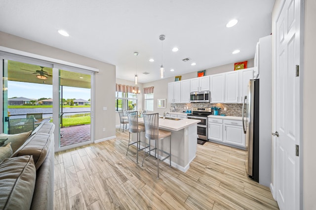 11187 SW Lake Park Dr, Port Saint Lucie, FL 34987 - kitchen featuring appliances with stainless steel finishes, open floor plan, light countertops, white cabinets, and a kitchen bar
