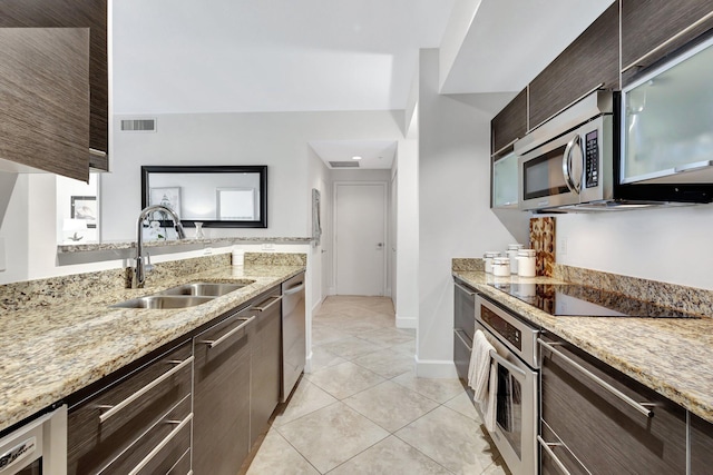 550 Okeechobee Blvd Unit 504, West Palm Beach, FL 33401 - kitchen with appliances with stainless steel finishes, a sink, dark brown cabinetry, light tile patterned flooring, and light stone counters