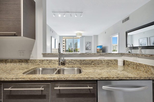 550 Okeechobee Blvd Unit 504, West Palm Beach, FL 33401 - kitchen with stainless steel dishwasher, a sink, rail lighting, dark brown cabinets, and light stone counters