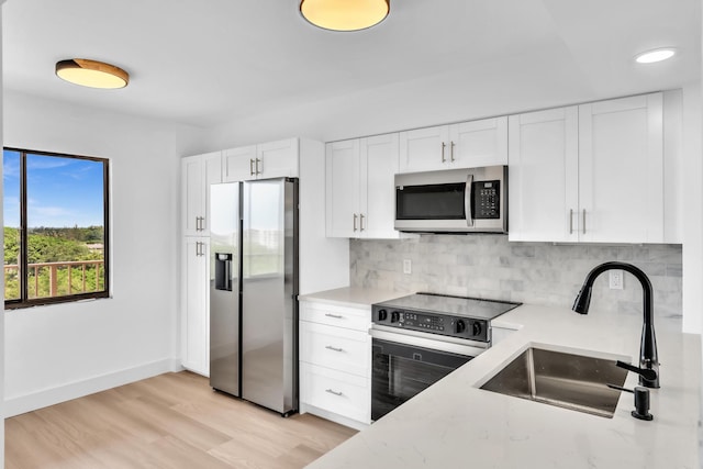 7076 Huntington Ln Unit 206, Delray Beach, FL 33446 - kitchen with appliances with stainless steel finishes, backsplash, white cabinetry, and light stone countertops