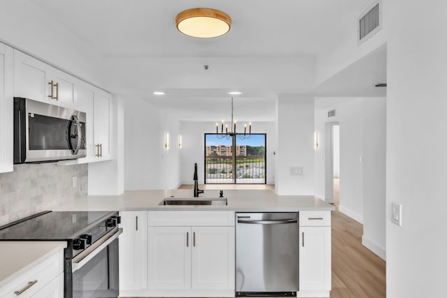 7076 Huntington Ln Unit 206, Delray Beach, FL 33446 - kitchen with appliances with stainless steel finishes, a peninsula, light countertops, tasteful backsplash, and a chandelier