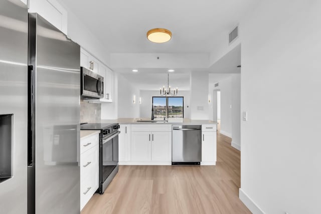 7076 Huntington Ln Unit 206, Delray Beach, FL 33446 - kitchen with stainless steel appliances, a peninsula, white cabinets, light wood finished floors, and recessed lighting