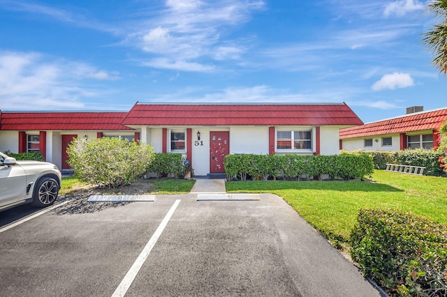 5800 Fernley Dr W Unit 51, Greenacres, FL 33415 - view of front facade featuring uncovered parking, mansard roof, and a front lawn