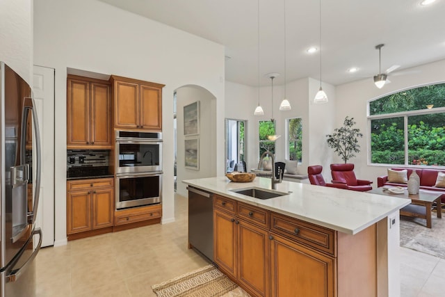 139 Sedona Way, Palm Beach Gardens, FL 33418 - kitchen with appliances with stainless steel finishes, a sink, arched walkways, brown cabinetry, and decorative backsplash