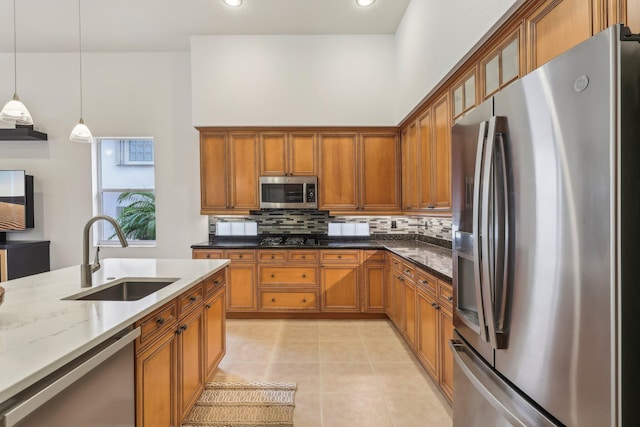 139 Sedona Way, Palm Beach Gardens, FL 33418 - kitchen featuring appliances with stainless steel finishes, a sink, brown cabinetry, decorative backsplash, and pendant lighting