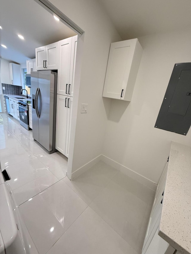 345 Pinehurst Rd, Palm Springs, FL 33461 - laundry room featuring electric panel, light tile patterned floors, baseboards, and a sink