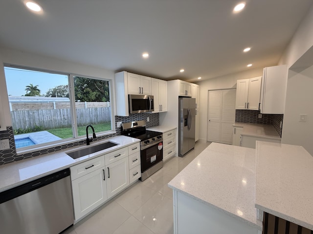 345 Pinehurst Rd, Palm Springs, FL 33461 - kitchen featuring appliances with stainless steel finishes, a sink, tasteful backsplash, white cabinets, and light stone counters