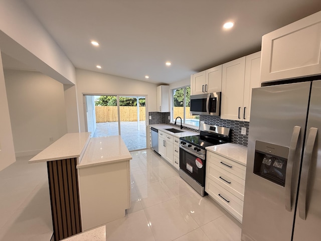 345 Pinehurst Rd, Palm Springs, FL 33461 - kitchen featuring appliances with stainless steel finishes, a sink, tasteful backsplash, a kitchen island, and white cabinetry