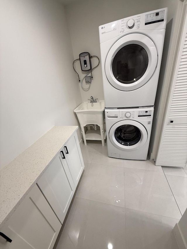 345 Pinehurst Rd, Palm Springs, FL 33461 - laundry room featuring stacked washer / dryer, cabinet space, and light tile patterned flooring