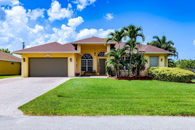 473 SW Dagget Ave, Port Saint Lucie, FL 34953 - view of front of house with stucco siding, an attached garage, a front lawn, and decorative driveway
