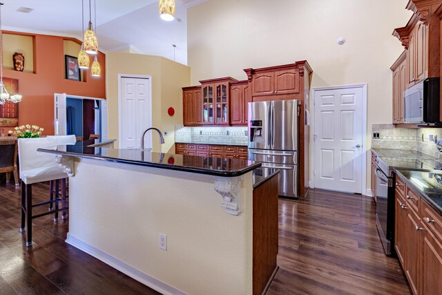 473 SW Dagget Ave, Port Saint Lucie, FL 34953 - kitchen with appliances with stainless steel finishes, a kitchen bar, a towering ceiling, and dark wood-style flooring