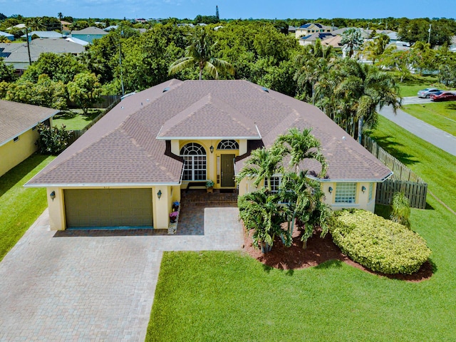 473 SW Dagget Ave, Port Saint Lucie, FL 34953 - view of front of house with an attached garage, stucco siding, decorative driveway, and roof with shingles