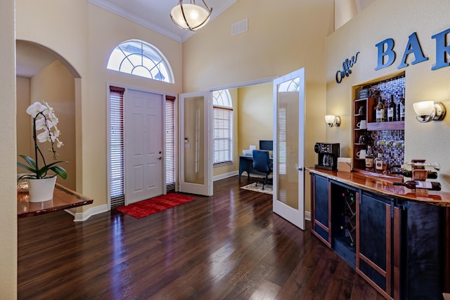 473 SW Dagget Ave, Port Saint Lucie, FL 34953 - entryway featuring wood finished floors, a dry bar, crown molding, arched walkways, and a towering ceiling