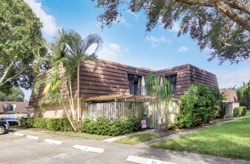2111 21st Ln, Palm Beach Gardens, FL 33418 - view of property exterior with mansard roof, uncovered parking, and brick siding