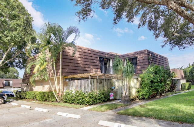 2111 21st Ln, Palm Beach Gardens, FL 33418 - view of property exterior with mansard roof, uncovered parking, and brick siding