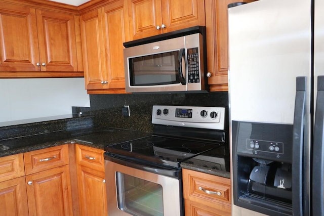 3507 Village Blvd Unit 401, West Palm Beach, FL 33409 - kitchen with stainless steel appliances, brown cabinetry, dark stone counters, and tasteful backsplash