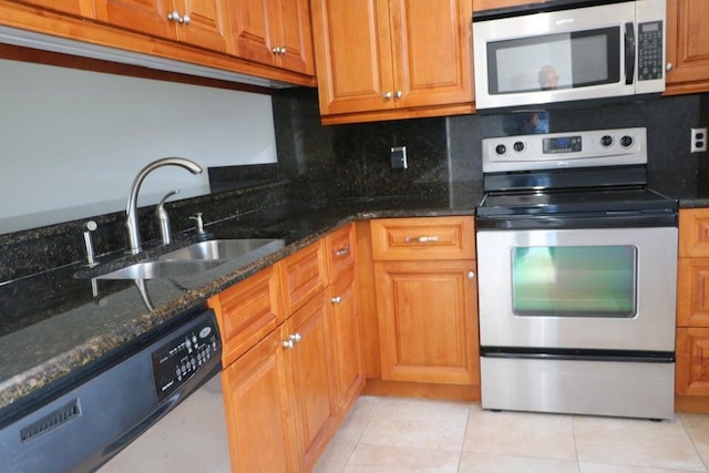 3507 Village Blvd Unit 401, West Palm Beach, FL 33409 - kitchen featuring appliances with stainless steel finishes, a sink, light tile patterned floors, tasteful backsplash, and dark stone counters