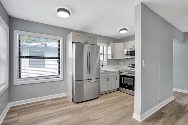 220 Walton Blvd, West Palm Beach, FL 33405 - kitchen featuring stainless steel appliances, light wood-style floors, light countertops, baseboards, and a textured ceiling