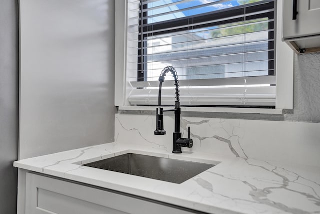 220 Walton Blvd, West Palm Beach, FL 33405 - kitchen view of a sink, decorative backsplash, light stone countertops, and white cabinets