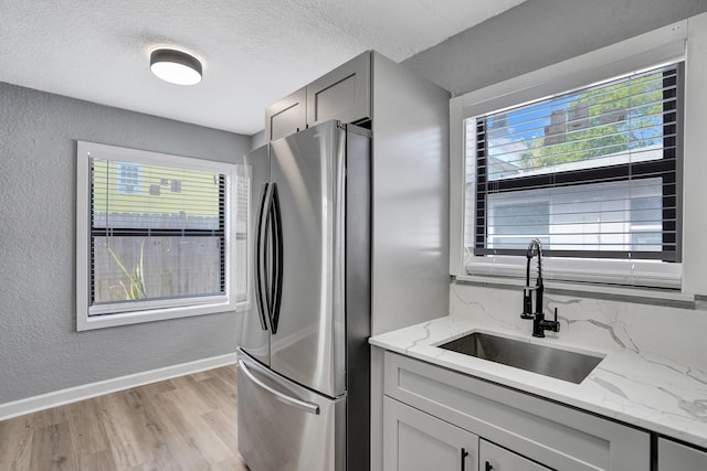 220 Walton Blvd, West Palm Beach, FL 33405 - kitchen with freestanding refrigerator, a sink, light wood-style floors, a textured ceiling, and light stone counters