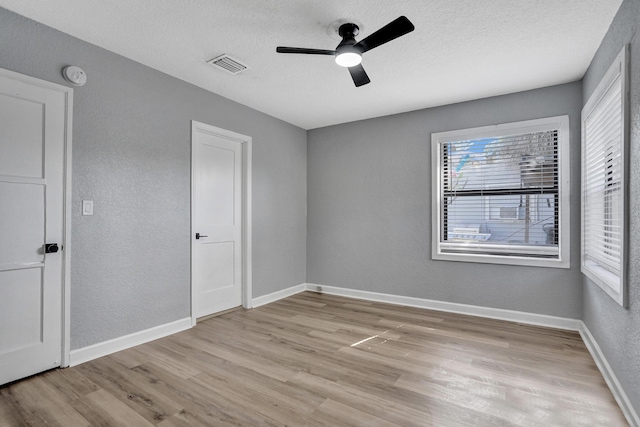 220 Walton Blvd, West Palm Beach, FL 33405 - unfurnished bedroom featuring light wood-style flooring, a textured wall, baseboards, a textured ceiling, and ceiling fan