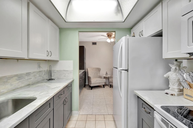 600 Pine Dr Unit 104, Pompano Beach, FL 33060 - kitchen with light tile patterned flooring, gray cabinets, a ceiling fan, white cabinets, and light stone counters