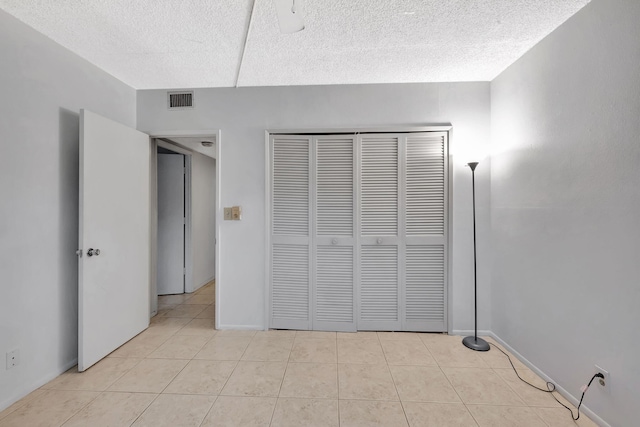 600 Pine Dr Unit 104, Pompano Beach, FL 33060 - unfurnished bedroom featuring light tile patterned floors, a textured ceiling, a closet, and baseboards