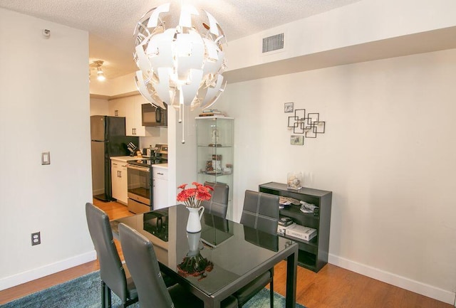 160 Yacht Club Way Unit 309, Hypoluxo, FL 33462 - dining room with a chandelier, baseboards, light wood-style floors, and a textured ceiling
