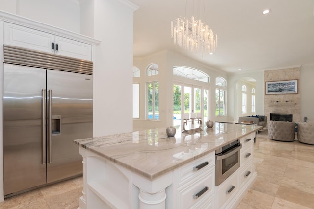 8246 Man O War Rd, Palm Beach Gardens, FL 33418 - kitchen featuring stainless steel built in fridge, a stone fireplace, arched walkways, light stone countertops, and recessed lighting
