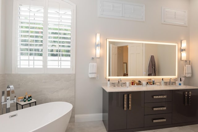 8246 Man O War Rd, Palm Beach Gardens, FL 33418 - full bathroom featuring a freestanding tub, double vanity, tile walls, and baseboards