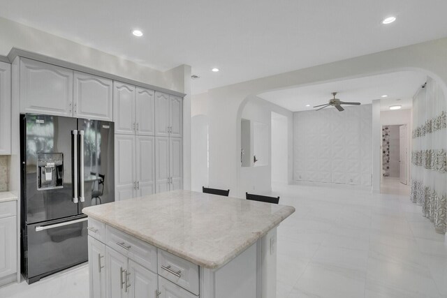 6164 C Durham Dr, Lake Worth, FL 33467 - kitchen with black fridge with ice dispenser, arched walkways, light stone countertops, a kitchen island, and ceiling fan