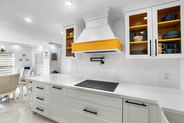 875 E Camino Real Unit 3E, Boca Raton, FL 33432 - kitchen featuring custom exhaust hood, light countertops, black electric cooktop, and glass insert cabinets