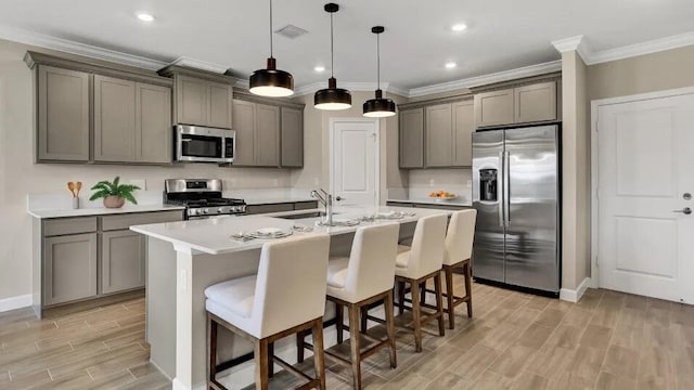 1681 Whistlegrass Ln, Loxahatchee, FL 33470 - kitchen with appliances with stainless steel finishes, ornamental molding, a sink, light wood-style floors, and a center island with sink