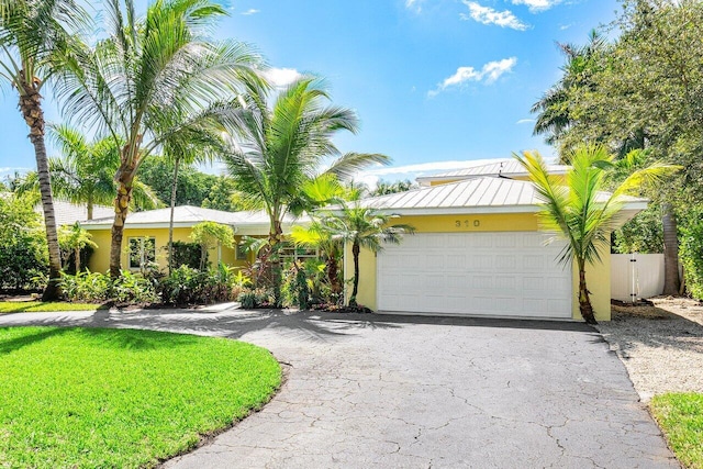 310 NW 18th St, Delray Beach, FL 33444 - view of front of home with curved driveway, stucco siding, an attached garage, and a standing seam roof