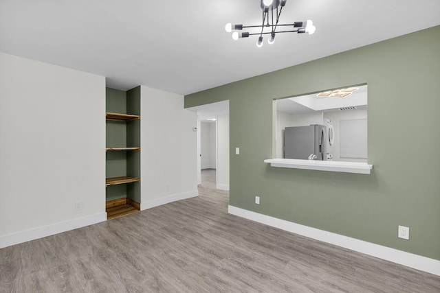 2517 S 17th St Unit 102, Fort Pierce, FL 34982 - spare room featuring wood finished floors, a chandelier, and baseboards