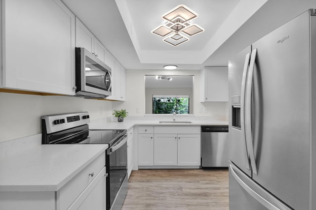 2517 S 17th St Unit 102, Fort Pierce, FL 34982 - kitchen featuring stainless steel appliances, a sink, white cabinetry, a tray ceiling, and light countertops