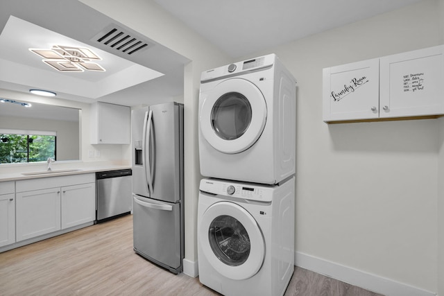 2517 S 17th St Unit 102, Fort Pierce, FL 34982 - laundry room featuring a sink, stacked washing machine and dryer, light wood-style flooring, and baseboards