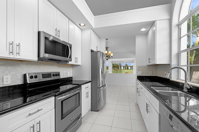 1415 Bear Island Dr, West Palm Beach, FL 33409 - kitchen with appliances with stainless steel finishes, a sink, a chandelier, light tile patterned floors, and white cabinetry