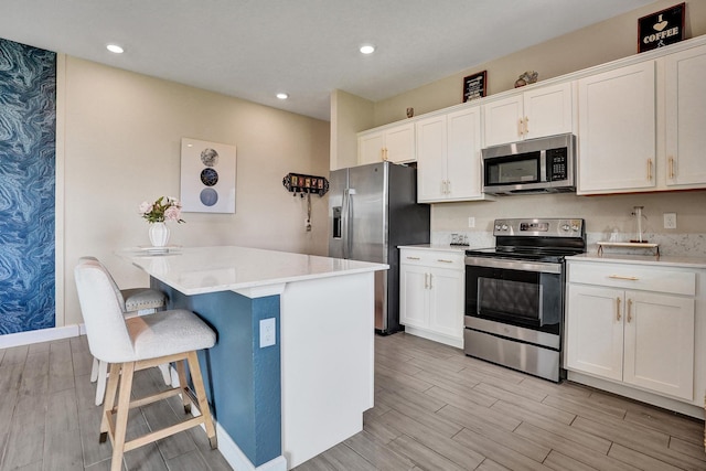 12623 NW Copper Creek Dr, Port Saint Lucie, FL 34987 - kitchen with stainless steel appliances, wood tiled floors, a breakfast bar area, white cabinets, and wallpapered walls
