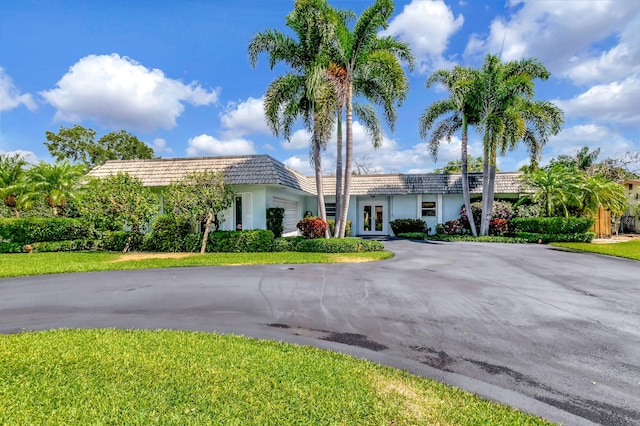 3913 Sherwood Blvd, Delray Beach, FL 33445 - view of front facade featuring french doors, asphalt driveway, an attached garage, and stucco siding